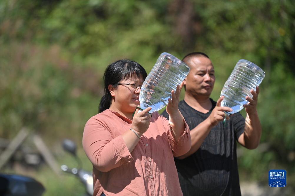 楊寧（左）在查看村民剛剛采集的水樣，為山泉水引水工程做準(zhǔn)備（10月8日攝）。新華社記者 黃孝邦 攝